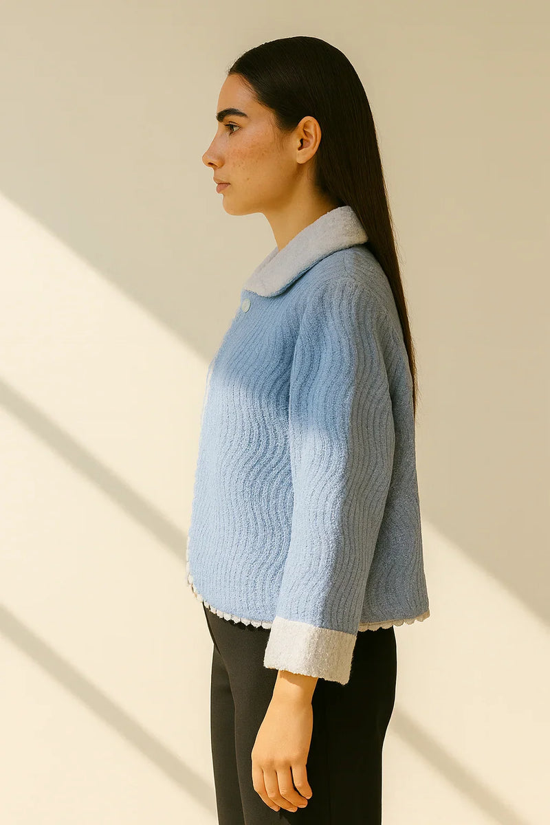 Woman wearing a light blue knitted sweater with a white collar against a beige background